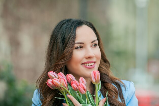 Portrait of a beautiful young woman in a blue suit with a bouquet of tulips