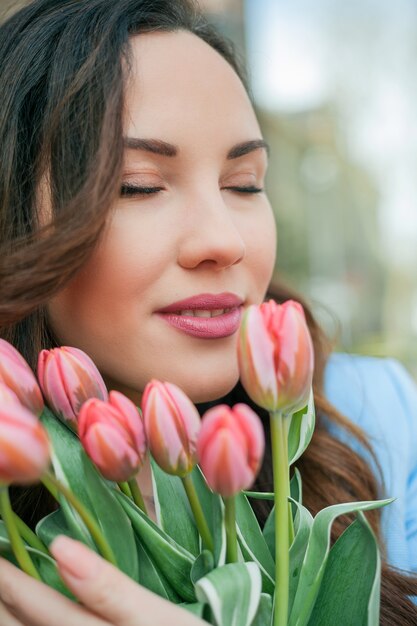 チューリップの花束と青いスーツを着た美しい若い女性の肖像画