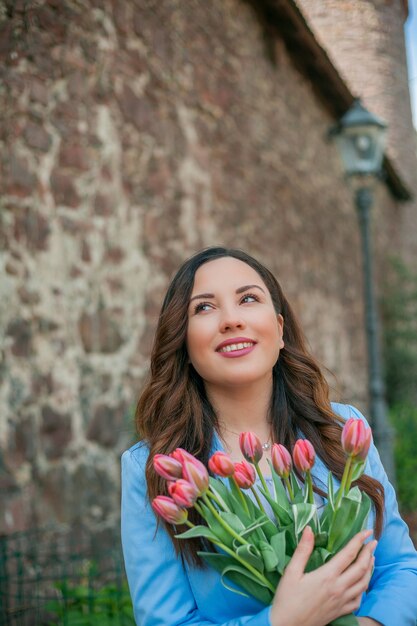 Portrait of a beautiful young woman in a blue suit with a bouquet of tulips