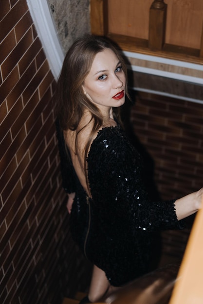 Портрет красивой молодой женщины с ярким вечерним макияжем и красными губами на лестнице готовится к