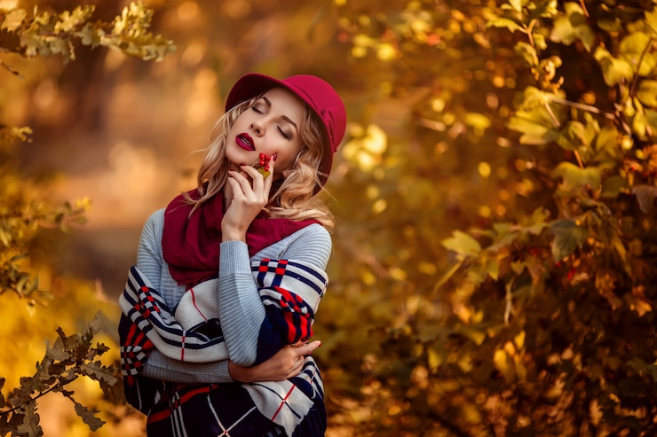 Photo portrait of a beautiful young woman in a burgundy hat in autumn on a walk in the park