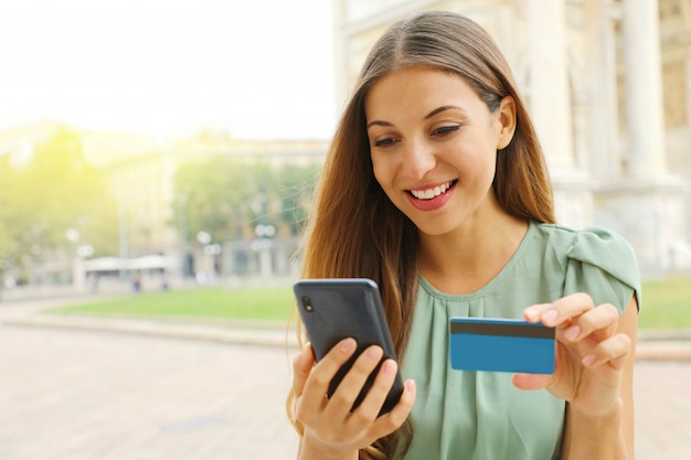 Portrait of a beautiful young woman buying online with a smart phone and credit card