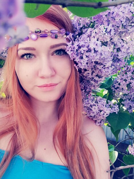 Portrait of beautiful young woman by flowering plant