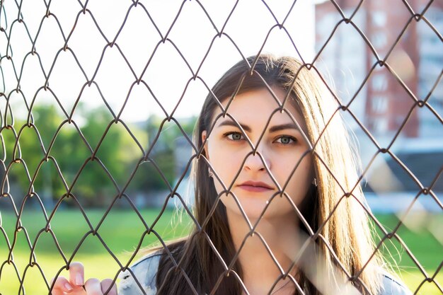 Foto ritratto di una bella giovane donna dietro una recinzione a catena