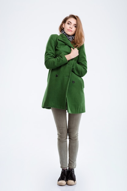 Portrait of a beautiful young woman in coat standing isolated on a white background and looking at camera