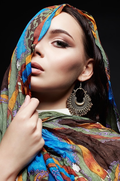 Portrait of beautiful young woman in color veil and jewelry