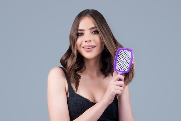 Portrait of beautiful young woman combing her hair smiling female brushing healthy hair with comb