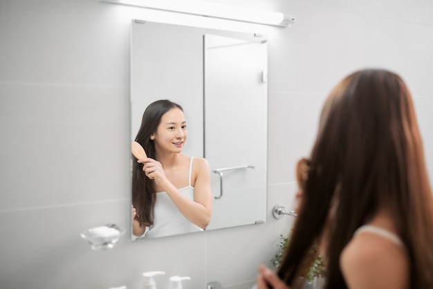 Portrait of a beautiful young woman combing her hair