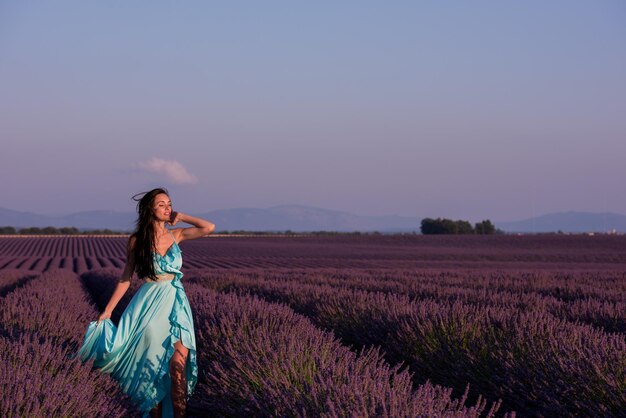 portrait of a beautiful young woman in cyand dress relaxing and having fun on wind at purple lavander flower field