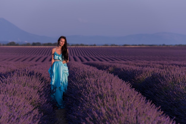 портрет красивой молодой женщины в голубом платье, расслабляющейся и веселящейся на ветру на фиолетовом цветочном поле лаванды