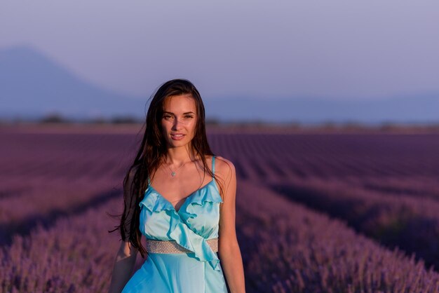 portrait of a beautiful young woman in cyand dress relaxing and having fun on wind at purple lavander flower field