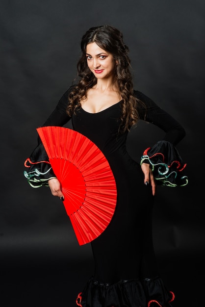 Photo portrait of beautiful young woman dancing flamenco with fan in studio