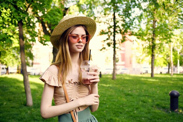 Portrait of beautiful young woman drinking in park