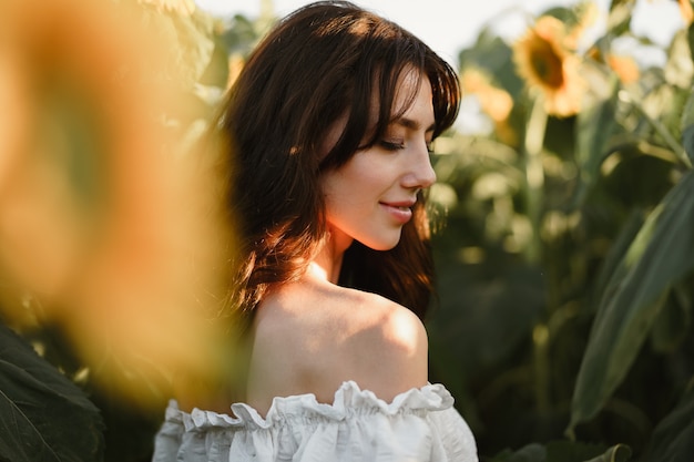 Portrait of beautiful young woman in a field of sunflowers