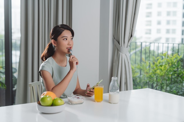 Ritratto di bella giovane donna che mangia prima colazione nella cucina