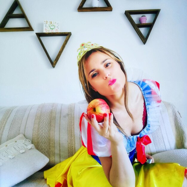 Portrait of beautiful young woman holding apple at home