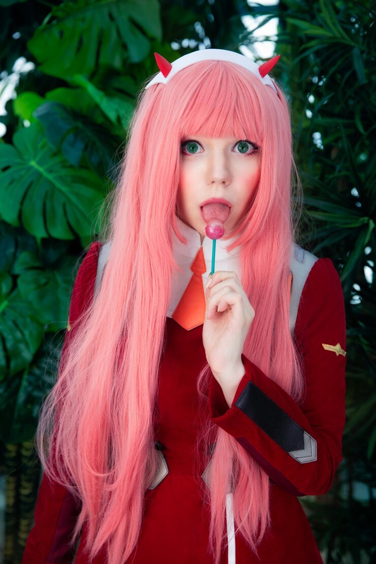 Photo portrait of beautiful young woman holding lollipop while standing against plants