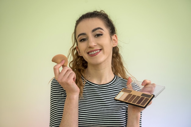 Portrait of beautiful young woman holding make-up brush  for makeup  morning before work. concept of beauty and health