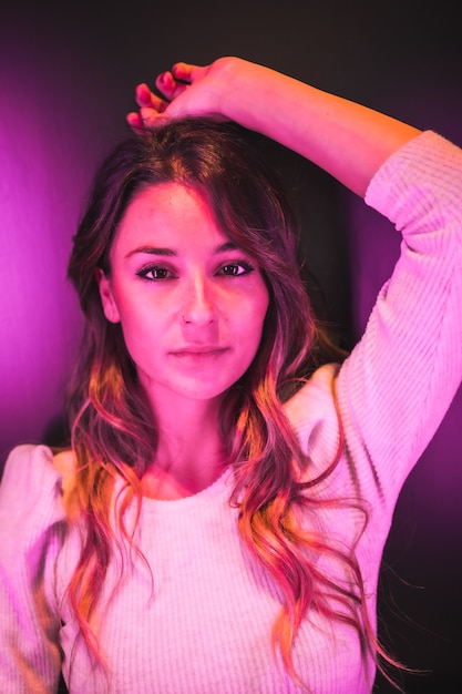 Portrait of a beautiful young woman looking at camera with pink led lights from the side