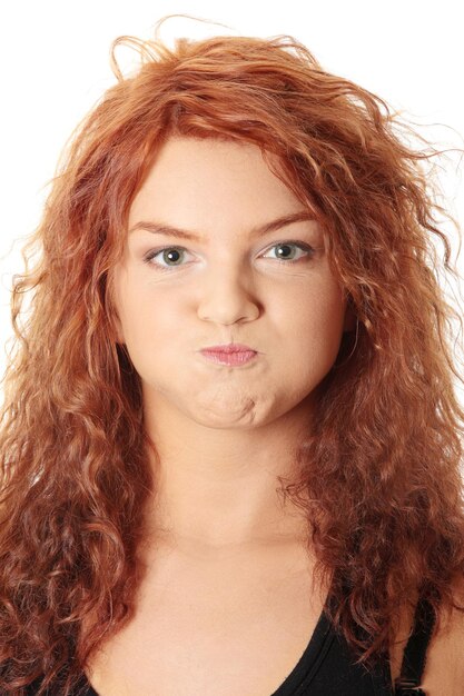 Photo portrait of beautiful young woman making a face against white background