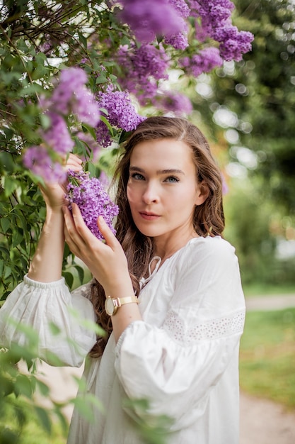 Portrait of a beautiful young woman near the blossoming lilac. Spring.