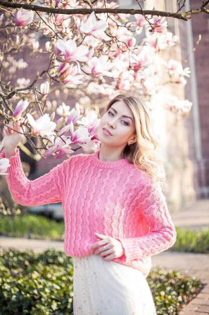 Portrait of a beautiful young woman near a magnolia. Spring.