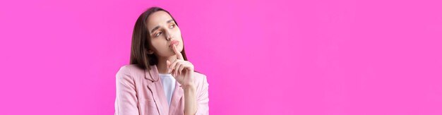 Portrait of beautiful young woman in pink jacket thinking isolated on red background