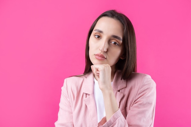 Portrait of beautiful young woman in pink jacket thinking isolated on red background