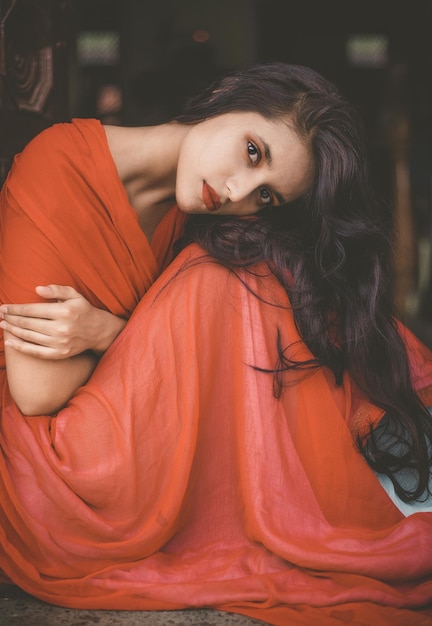 Photo portrait of beautiful young woman in red dress sitting at home