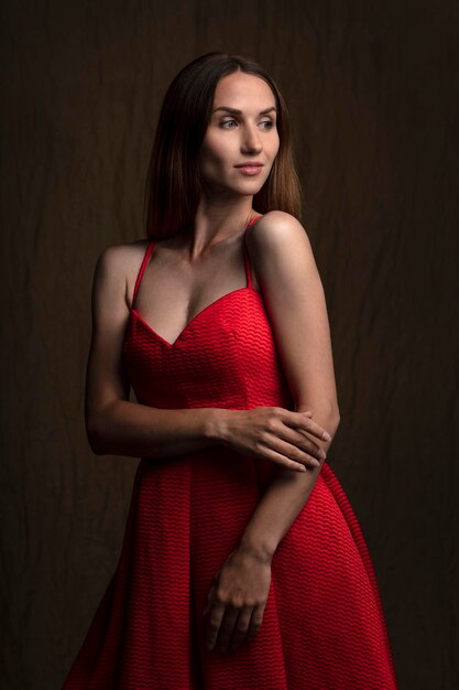 portrait of a beautiful young woman in a red dress studio shot on a dark background