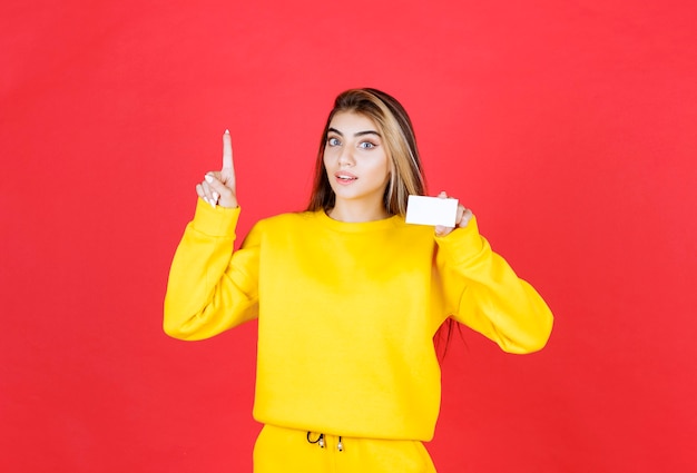 Portrait of beautiful young woman showing blank business card