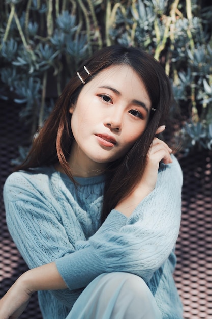 植物に背を向けて座っている美しい若い女性の肖像画