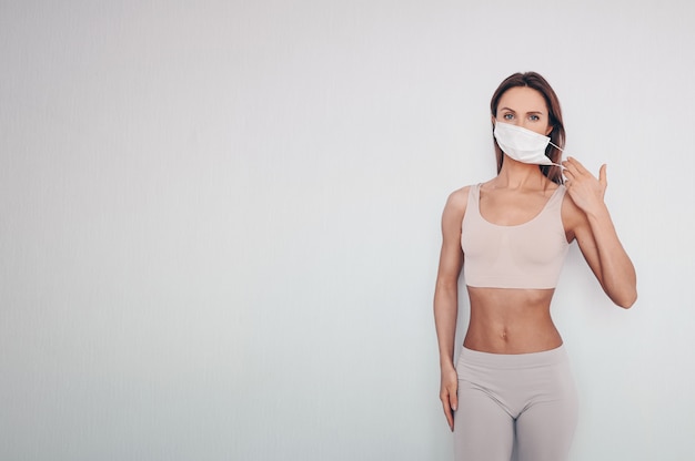 Ritratto di bella giovane donna in abiti sportivi che indossano maschera protettiva