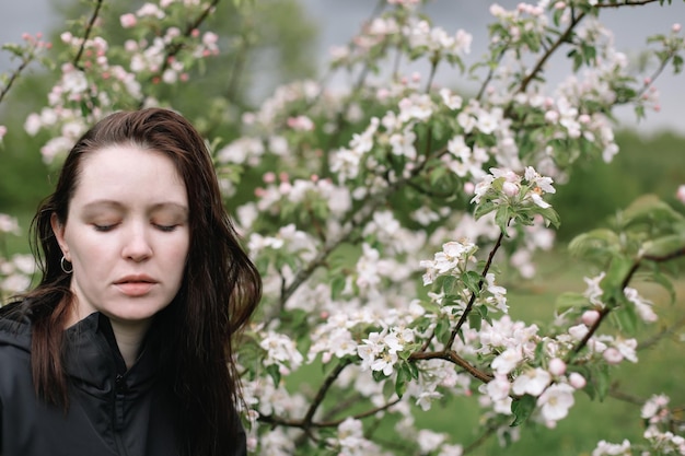 リンゴの花に囲まれた春の庭で美しい若い女性の肖像画