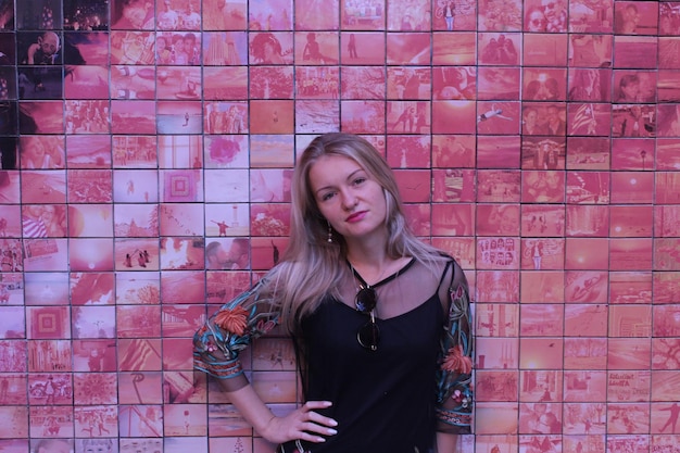 Portrait of beautiful young woman standing against brick wall