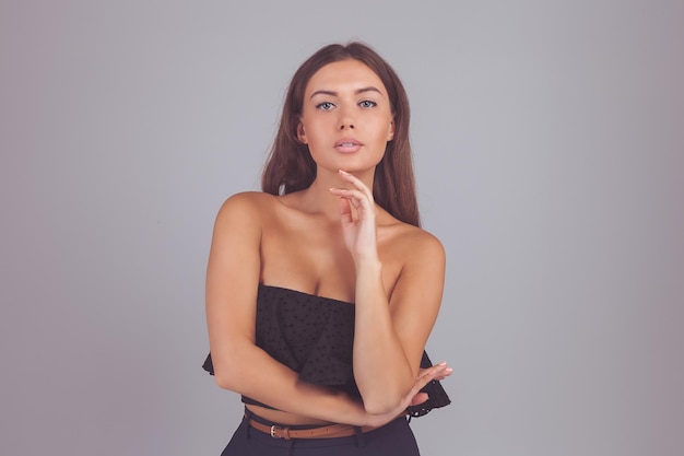 灰色の背景に立っている美しい若い女性の肖像画