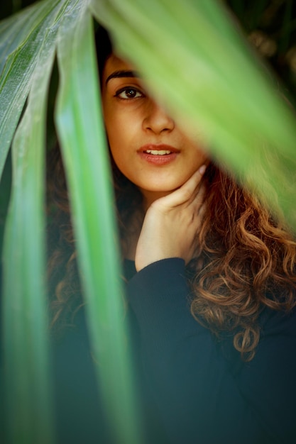 Portrait of beautiful young woman standing against plants