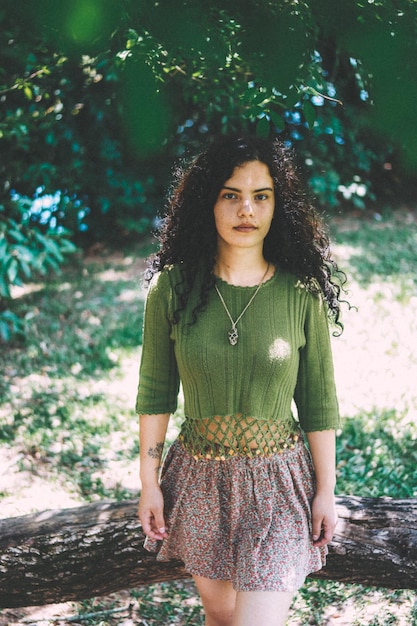 Portrait of beautiful young woman standing against trees