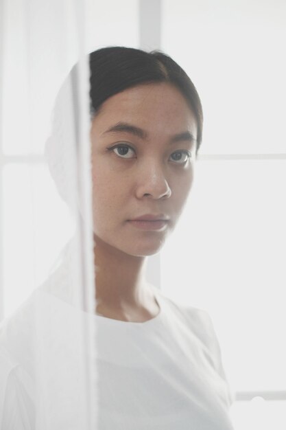 Photo portrait of beautiful young woman standing against window