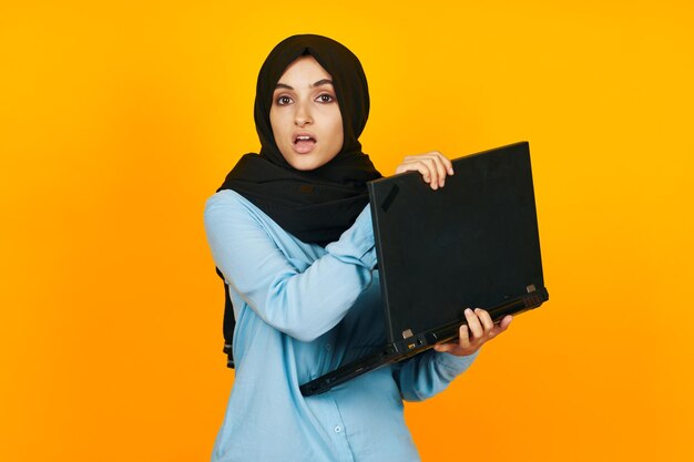 Portrait of beautiful young woman standing against yellow background