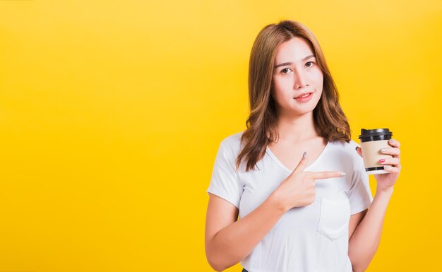 Portrait of beautiful young woman standing against yellow background