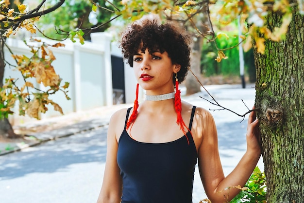 Foto ritratto di una bella giovane donna in piedi vicino al tronco di un albero