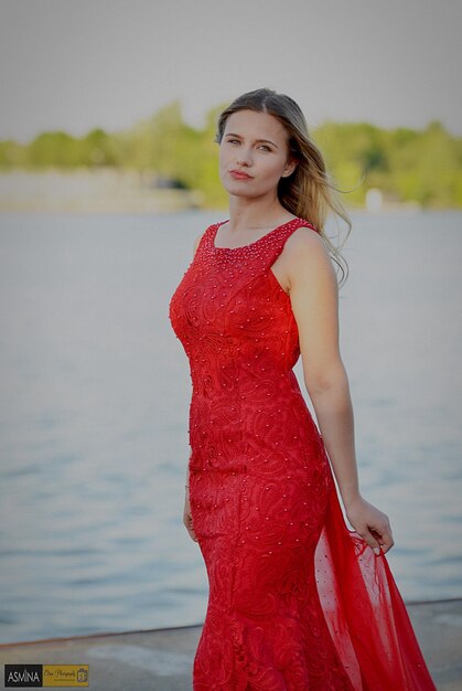 Portrait of beautiful young woman standing wearing red dress outdoors