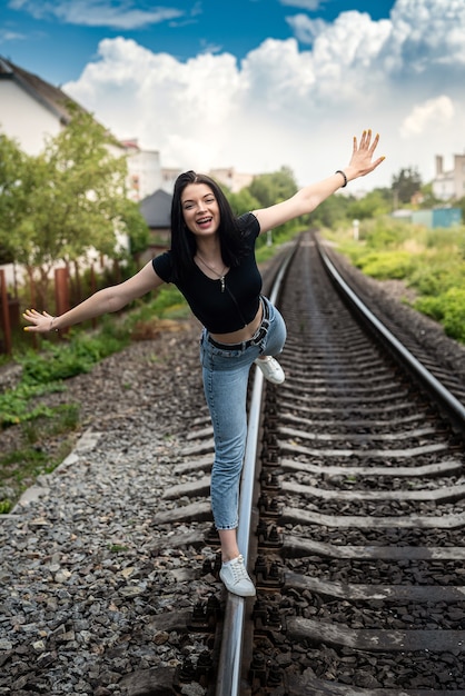 Portrait of beautiful young woman in summer cloth posing near railway, trip