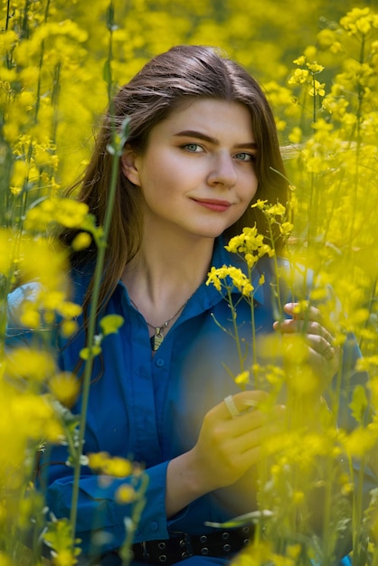 Portrait of a beautiful young woman surrounded by canola flowers