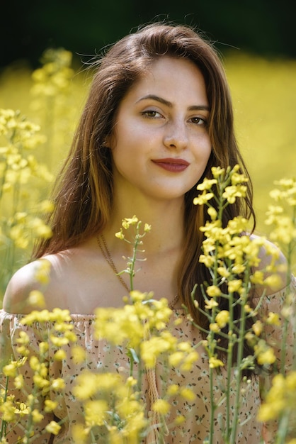 Portrait of a beautiful young woman surrounded by canola flowers