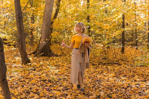 Portrait of beautiful young woman walking outdoors in autumn fall season and stylish girl concept