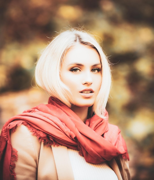 Portrait of beautiful young woman walking outdoors in autumn Fashion woman in autumn country style Closeup face of happy girl with red scarf