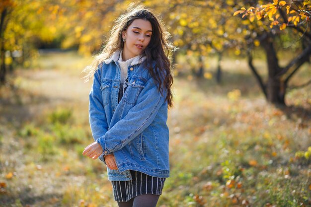 Portrait of beautiful young woman walking outdoors in autumn park