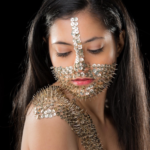 Portrait of a beautiful young woman wearing body armour made of thumbtacks